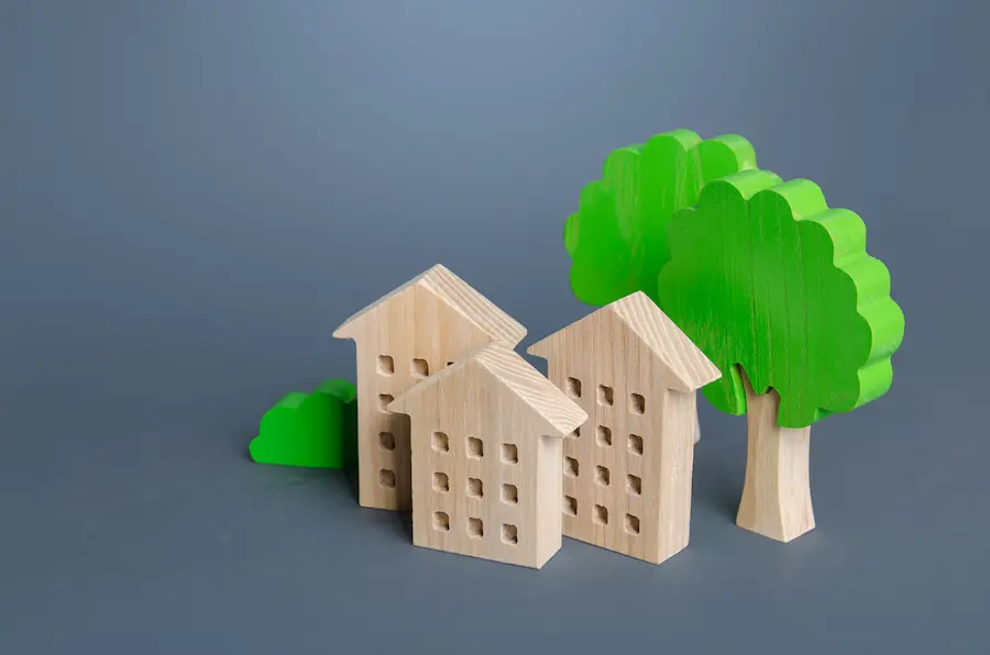 Wooden toy houses and green trees on a gray background.